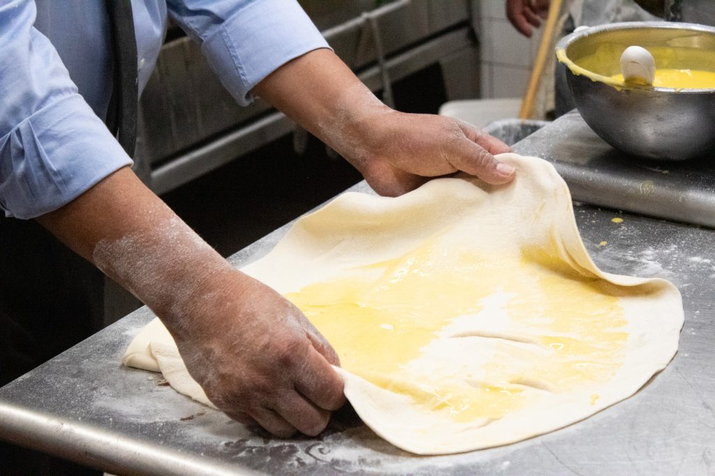 Mariano spreads out dough for the restaurant's Mediterranean Bread. The dough was lathered heavily with garlic butter before reaching the oven. Photographed by Finn Martin/BruinLife.
