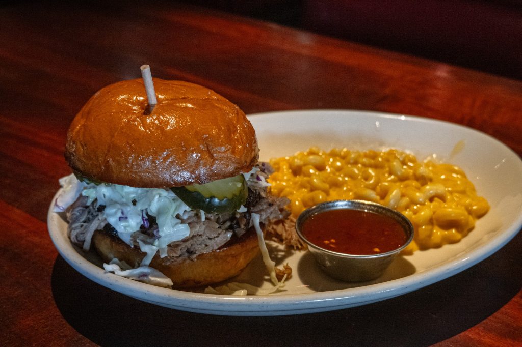 One of the lightest barbecue sandwiches you'll try in your life, the pulled pork sandwich shows up with its carefully prepared pork, Carolina slaw and pickles. The Mac and Cheese companion came as a carefully proportioned but heavy side piece to this dish. Photo by Finn Martin/BruinLife.