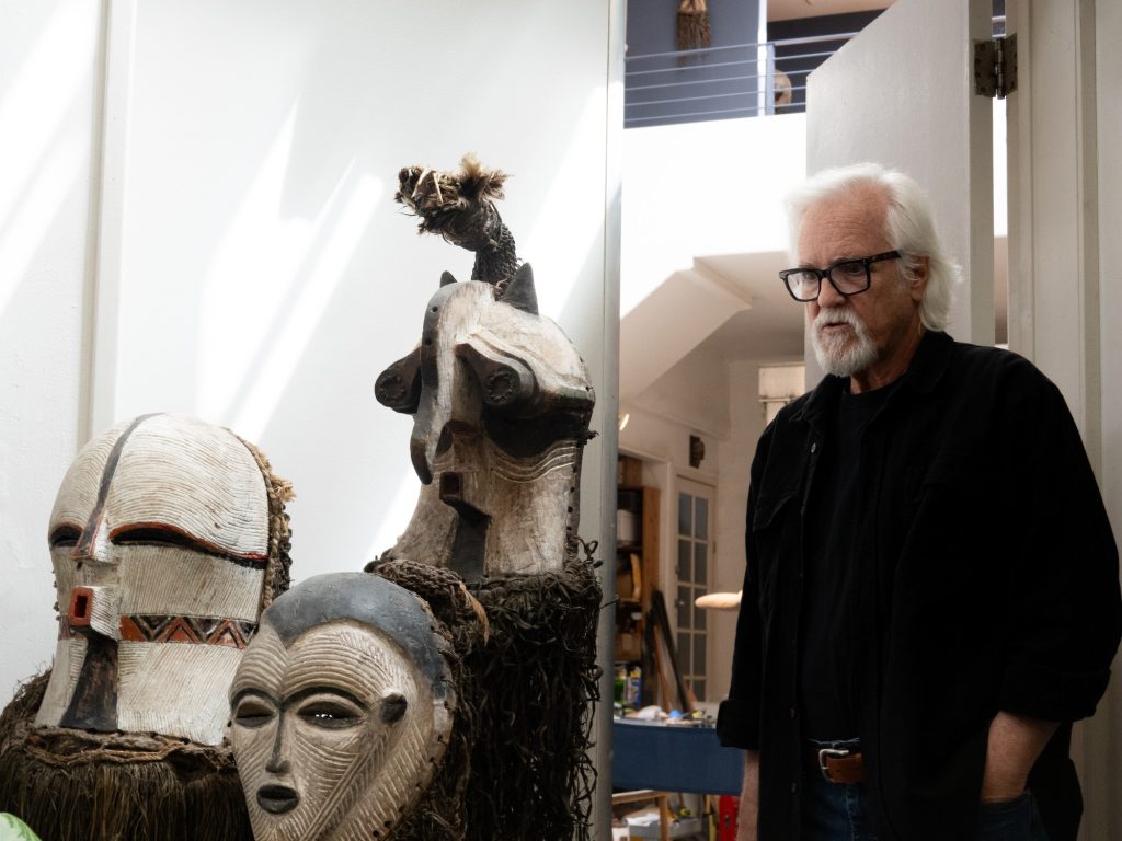 Woods Davy stands at the doorway between his living room and his stone studio. Photographed by Finn Martin/BruinLife.
