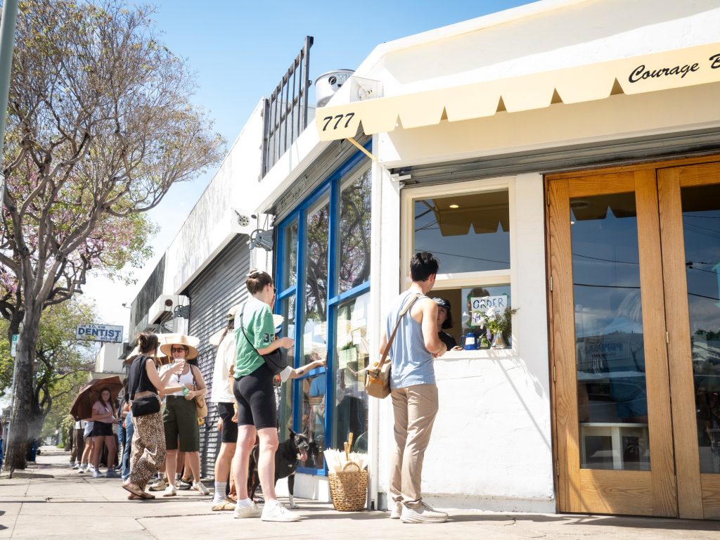 Patrons queue along the block with Courage Bagel-provided parasols and mist spray. Photographed by Finn Martin/BruinLife.
